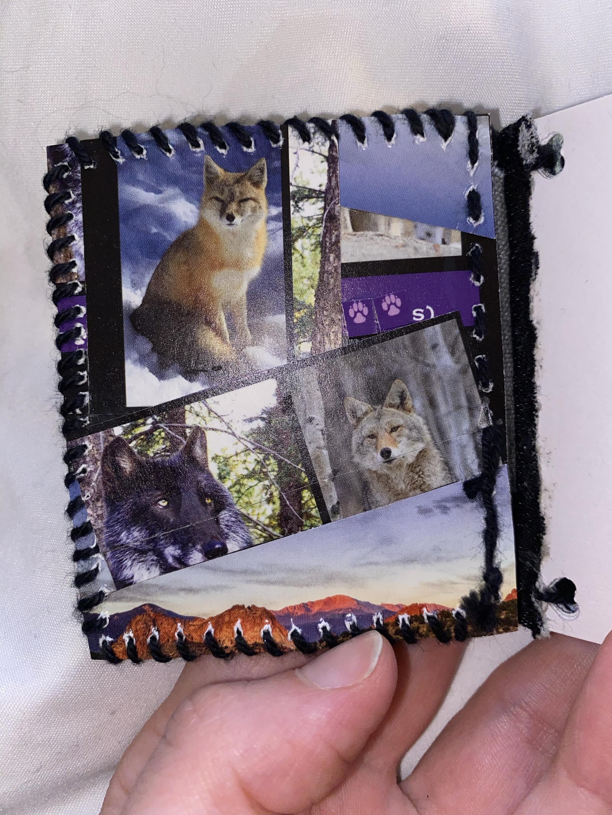 A small, handmade book cover featuring images of various wolves and a fox, with a stitched spine and a background of soft fabric.
